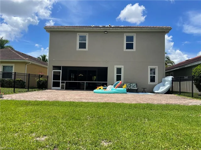 Back of property with a patio and lawn.