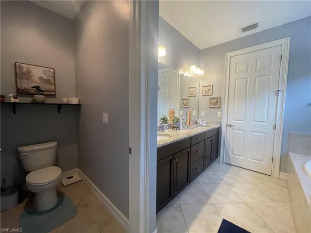 Bathroom featuring a tub to relax in, double sink vanity, private toilet space.