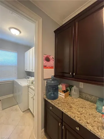 Laundry room with separate washer and dryer, cabinets.
