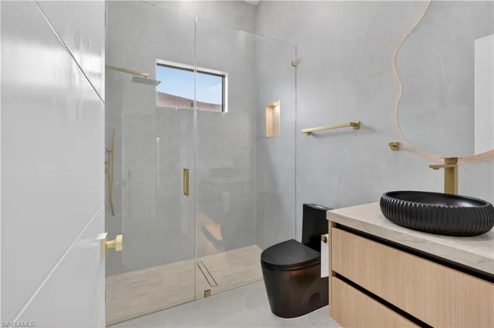 Glass-enclosed shower with a rainfall showerhead and handheld sprayer