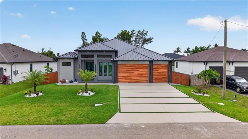 Contemporary single-story residence with a metal roof and a spacious, segmented driveway