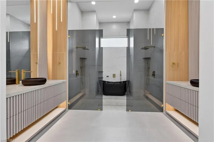 Contemporary bathroom featuring dual floating vanities with reeded paneling and integrated lighting