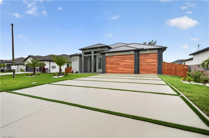 Contemporary exterior featuring a metal roof and a patterned concrete driveway with artificial turf accents