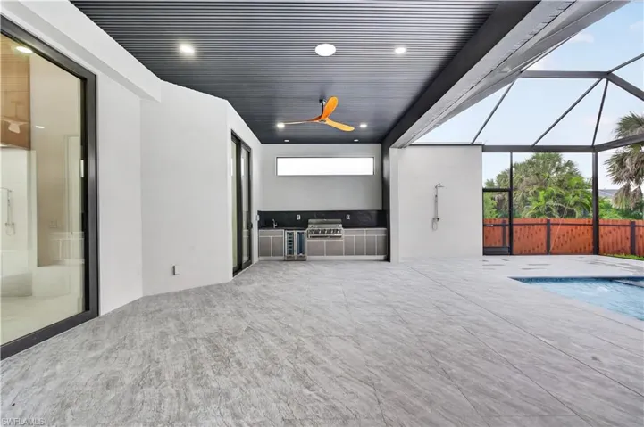 Expansive outdoor living area featuring a screened-in pool enclosure with a dark metal frame