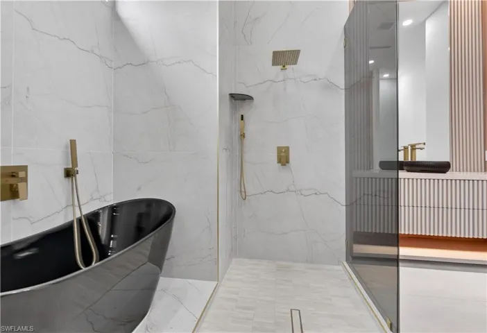 Freestanding black soaking tub with wall-mounted brass fixtures