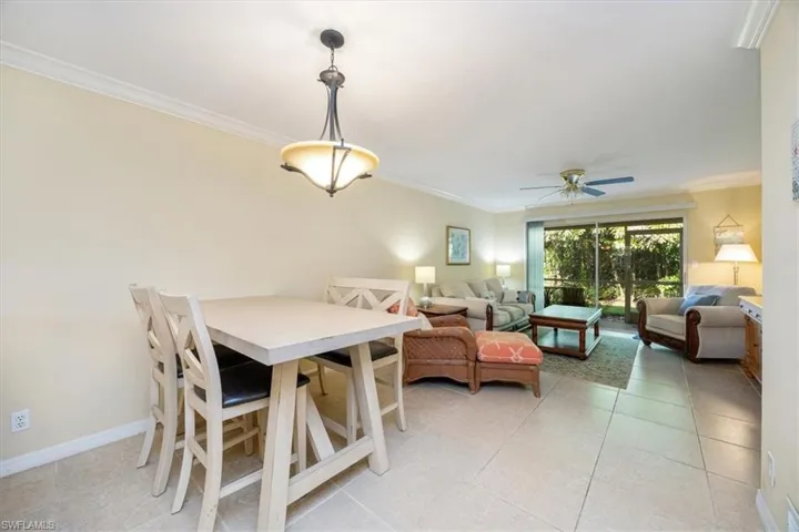 Dining room with crown molding, light tile patterned floors, and ceiling fan