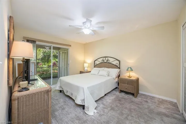 Carpeted bedroom featuring ceiling fan and access to exterior