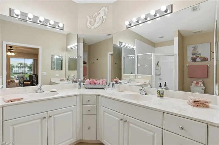 Ensuite bathroom featuring double vanity, a stall shower, and ceiling fan