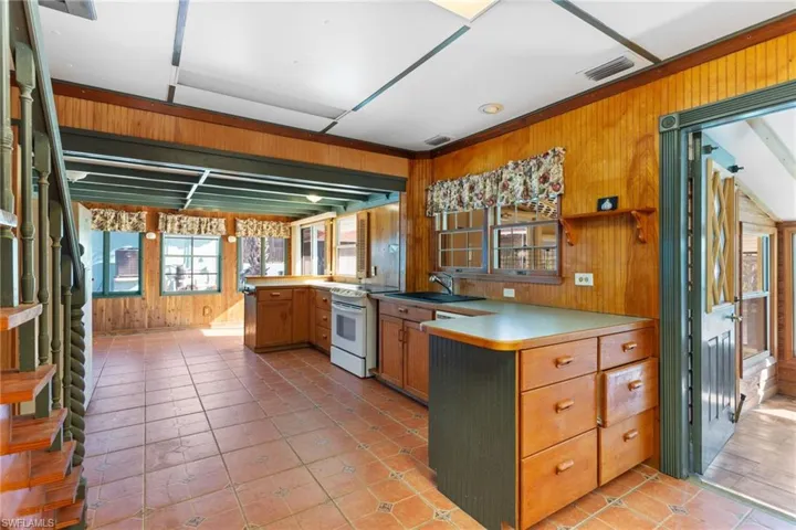 Kitchen featuring wood walls, a peninsula, wood finish cabinetry, white range with electric cooktop, and light countertops