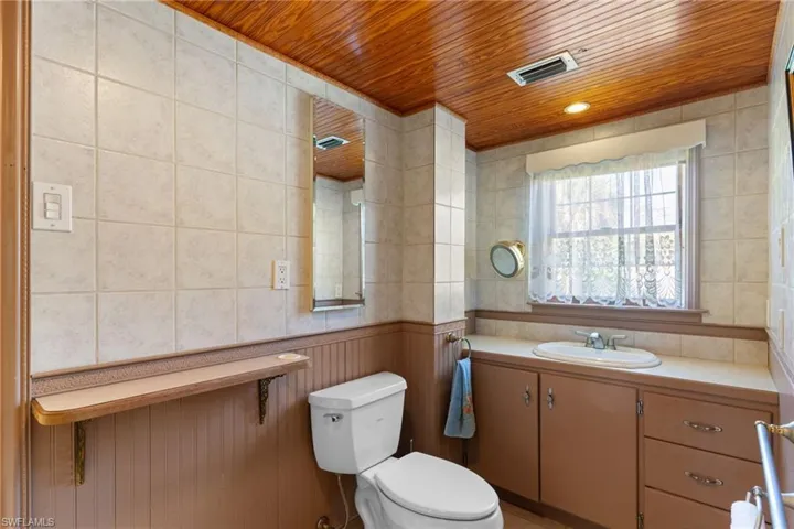 Half bathroom with vanity, tile walls, and wooden ceiling