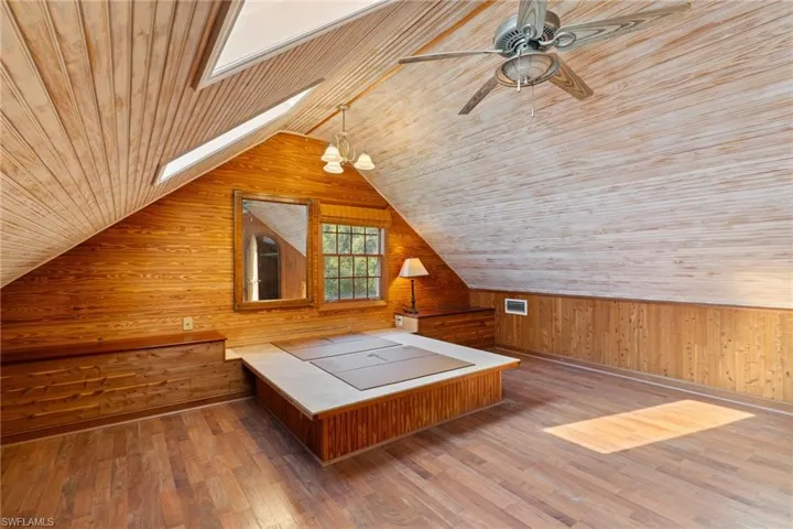 Additional living space featuring wood walls, hardwood / wood-style floors, wooden ceiling, and a skylight