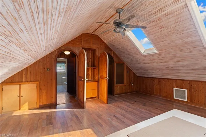 Additional living space featuring wood walls, hardwood / wood-style flooring, ceiling fan, wood ceiling, and a skylight