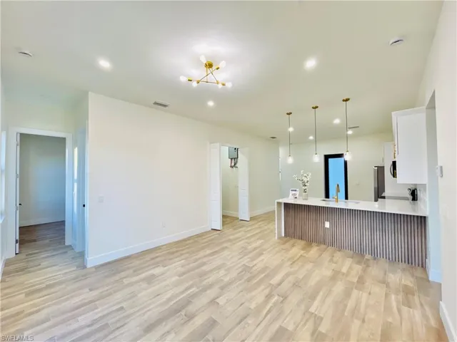 Kitchen featuring decorative light fixtures, white cabinets, recessed lighting, a kitchen breakfast bar, and a peninsula