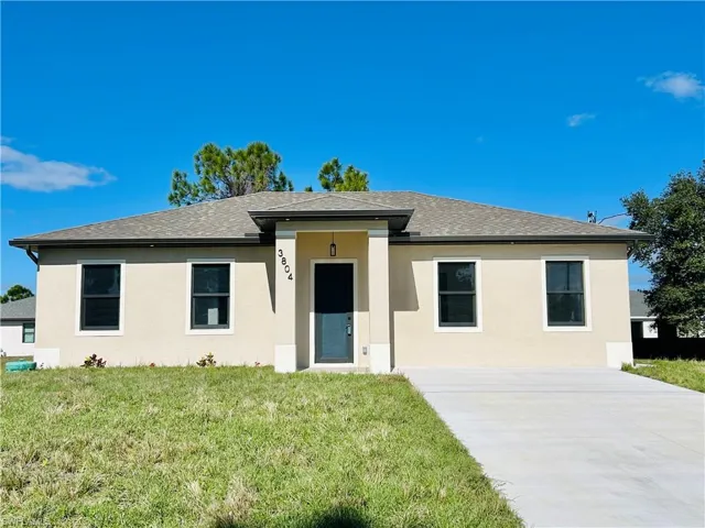 Ranch-style house with a front lawn, stucco siding, a shingled roof, and concrete driveway