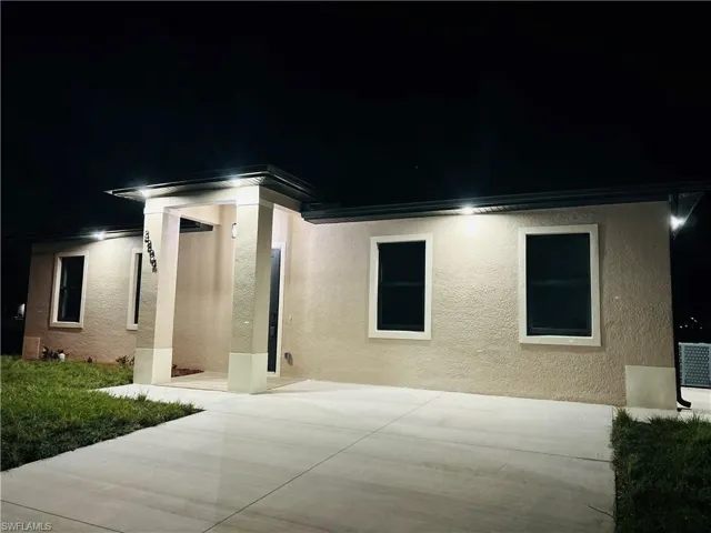 Back of house at twilight featuring stucco siding