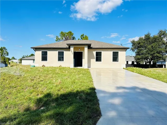 View of front of property featuring stucco siding, a front lawn, and driveway