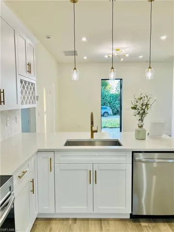 Kitchen with white cabinetry, stainless steel appliances, light stone countertops, hanging light fixtures, and recessed lighting