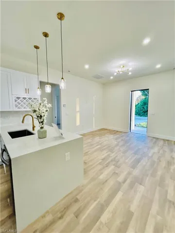 Kitchen featuring white cabinetry, hanging light fixtures, light stone countertops, open floor plan, and recessed lighting