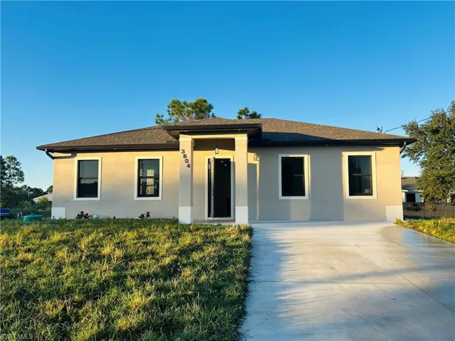 View of front of home with stucco siding, concrete driveway, and roof with shingles
