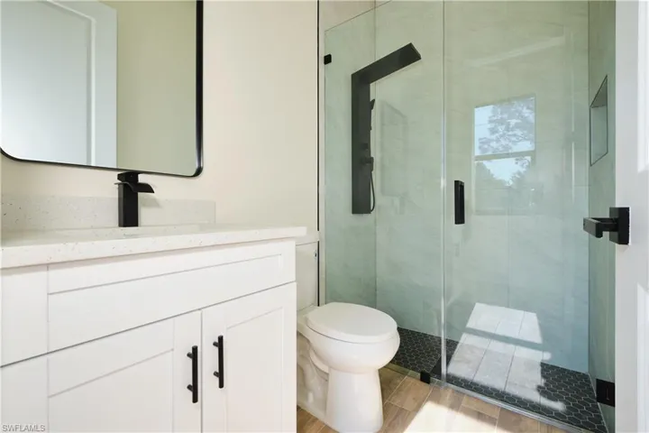 Full bath featuring vanity, a shower stall, and wood tiled floors