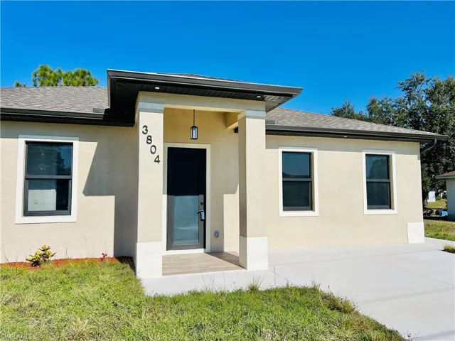 Doorway to property with roof with shingles and stucco siding