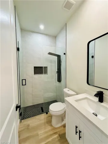 Full bathroom featuring vanity, a stall shower, and light wood-type flooring