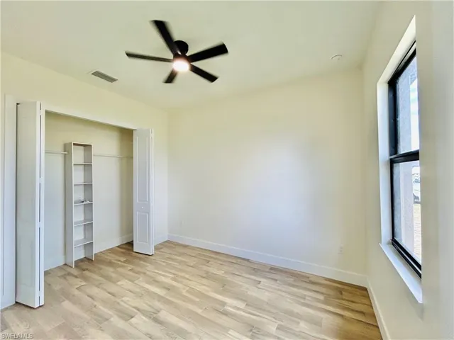 Unfurnished bedroom with light wood-type flooring, ceiling fan, and a closet