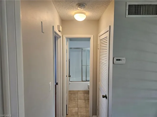 Hallway featuring tile patterned floors and a textured ceiling