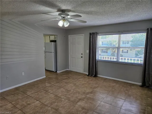 Tiled empty room featuring a textured ceiling and ceiling fan