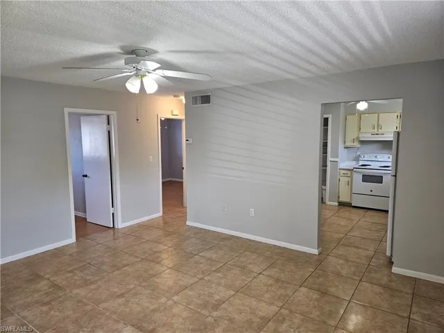 Tiled spare room with ceiling fan and a textured ceiling