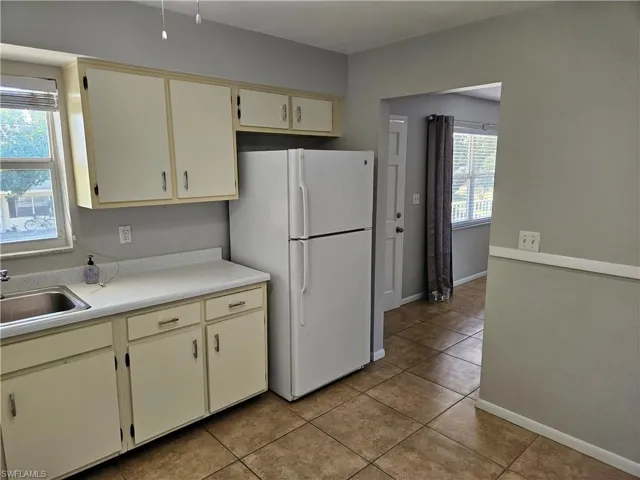 Kitchen with cream cabinetry, white refrigerator, a healthy amount of sunlight, and sink