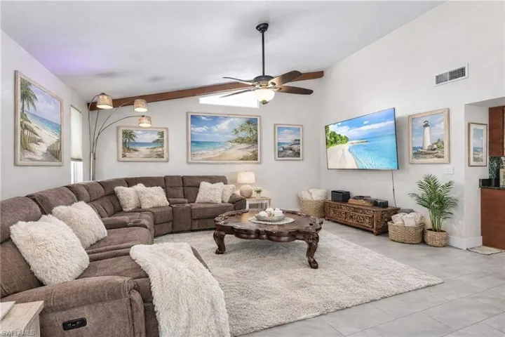 Living area featuring ceiling fan and lofted ceiling with beams