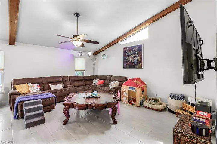 Living area featuring vaulted ceiling with beams and a ceiling fan