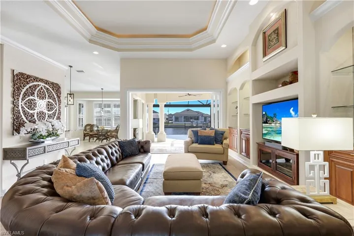 Living area featuring built in features, ornamental molding, recessed lighting, and a raised ceiling