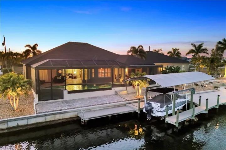 Dock featuring boat lift, a water view, a lanai, a sunroom, and an outdoor pool