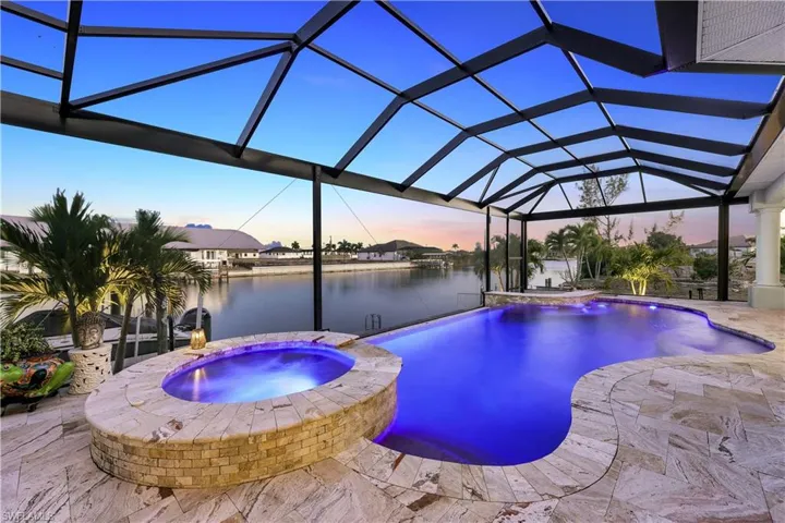 Integrated pool / spa featuring a sunroom, glass enclosure, a patio, and a water view
