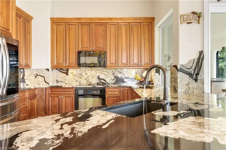 Kitchen featuring light stone countertops, wood finish cabinets, and black appliances