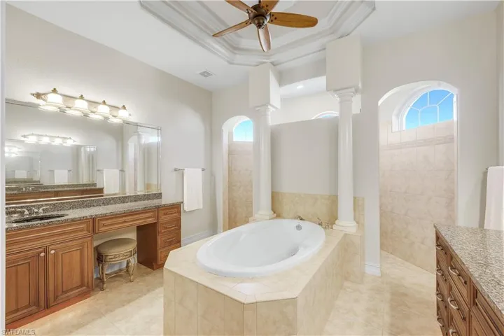 Bathroom featuring vanity, a walk in shower, a garden tub, and light tile patterned floors