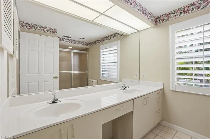 Primary Bathroom with double vanity, a stall shower, and light tile patterned floors