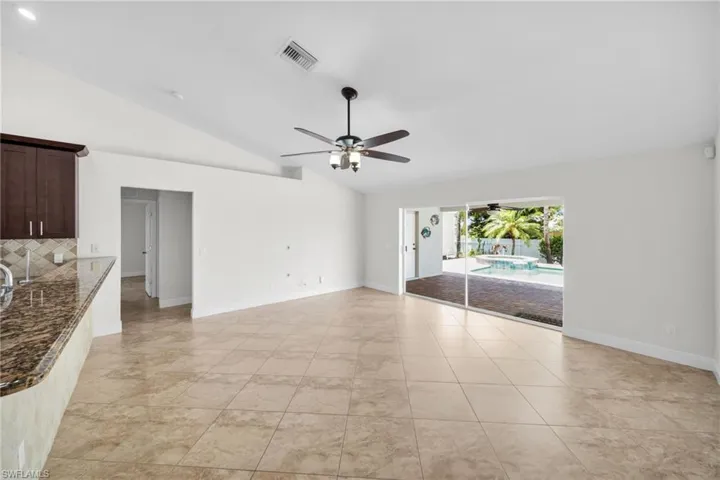Unfurnis'hed living room with lofted ceiling, a ceiling fan, and light tile patterned flooring