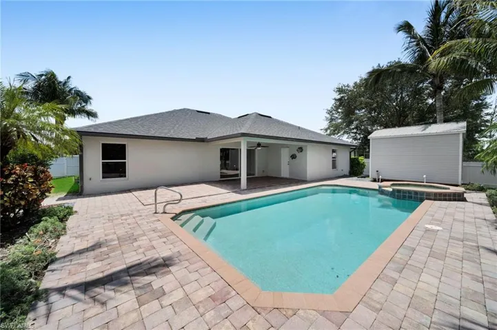 View of pool with a patio, ceiling fan, a pool with connected hot tub, and an outdoor structure