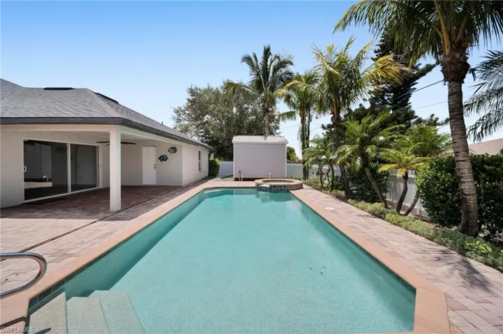 Vie'w of swimming pool with a patio area, a pool with connected hot tub, and an outbuilding