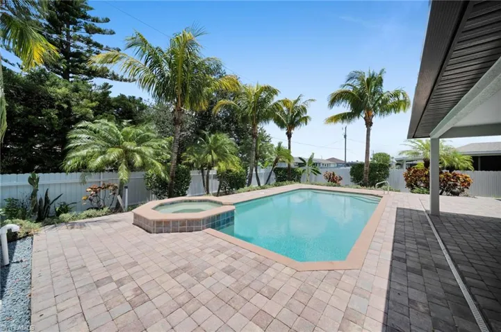 View of pool featuring a patio, a fenced backyard, and a pool with connected hot tub