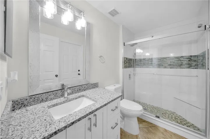 Full bathroom featuring a shower stall, vanity, and tile patterned floors