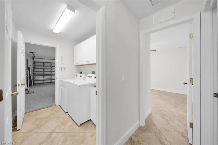 Washroom with cabinet space, washer and clothes dryer, and light tile patterned floors