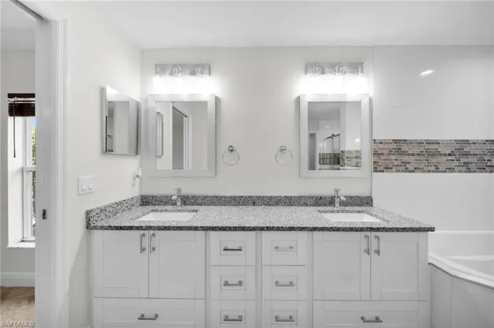 Full bath with double vanity, a tub to relax in, and a shower