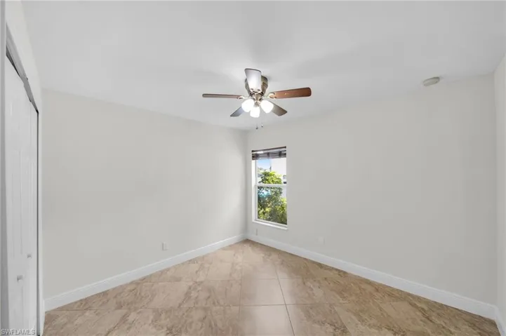 Unfurnished bedroom featuring a closet, light tile patterned flooring, and ceiling fan