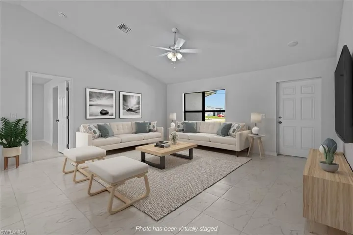 Living area with vaulted ceiling, light marble finish floors, and ceiling fan
