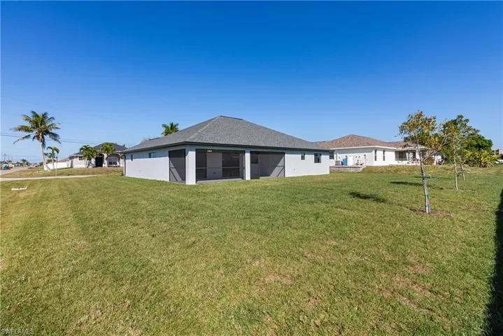 Back of property featuring a yard, a sunroom, and a shingled roof