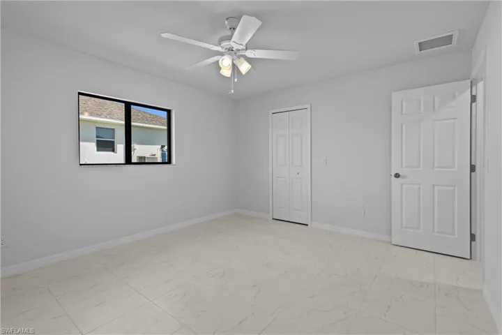 Unfurnished bedroom featuring light marble finish flooring, a ceiling fan, and a closet